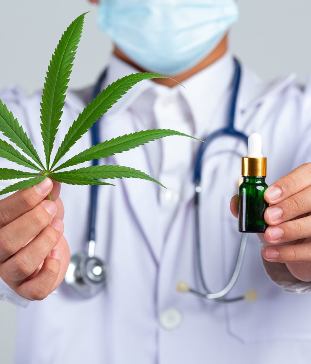 medical-doctor-holding-cannabis-leaf-bottle-cannabis-oil-white-wall (1)